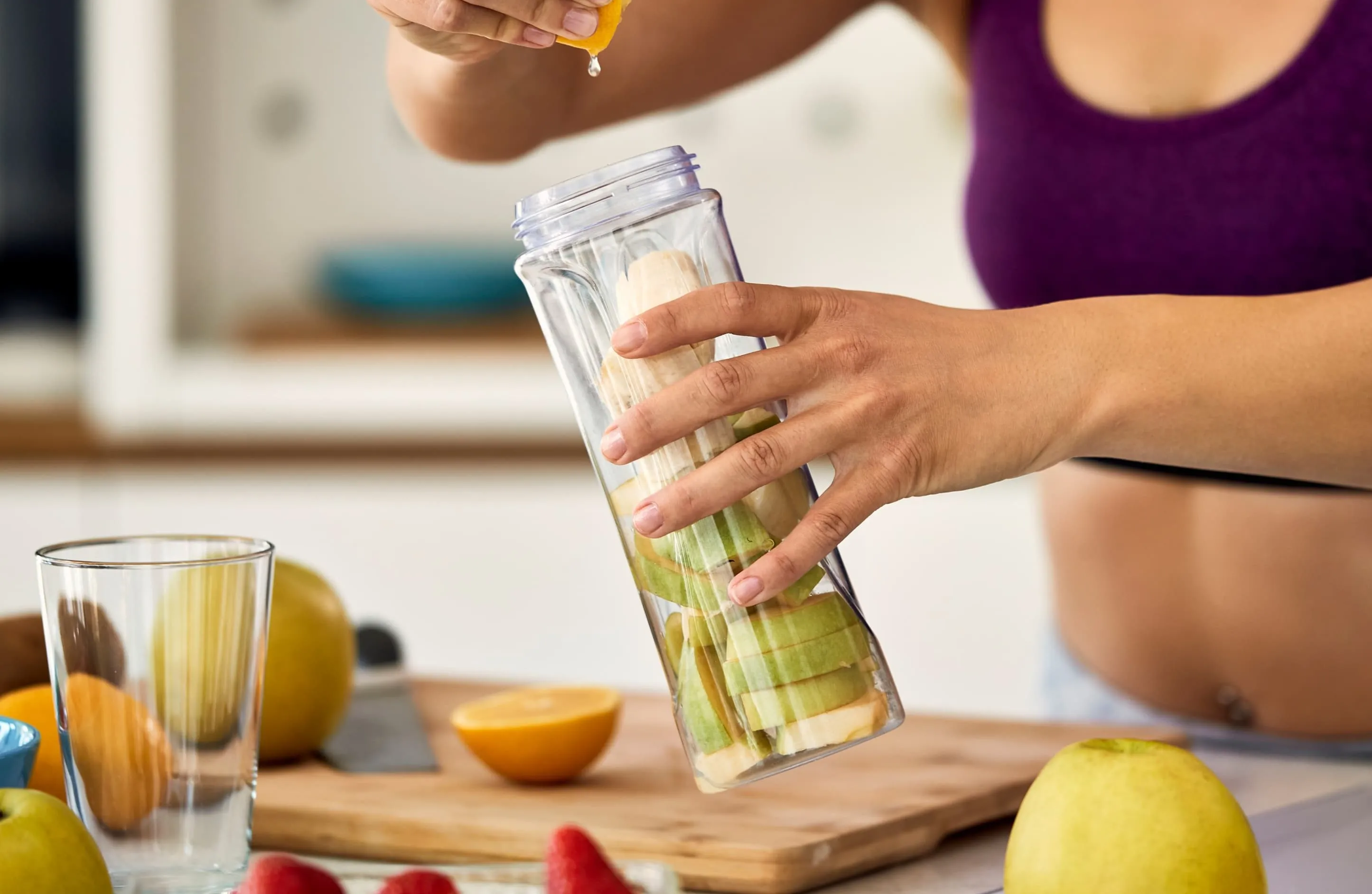 unrecognizable-sportswoman-using-lemon-while-making-fruit-smoothie-home